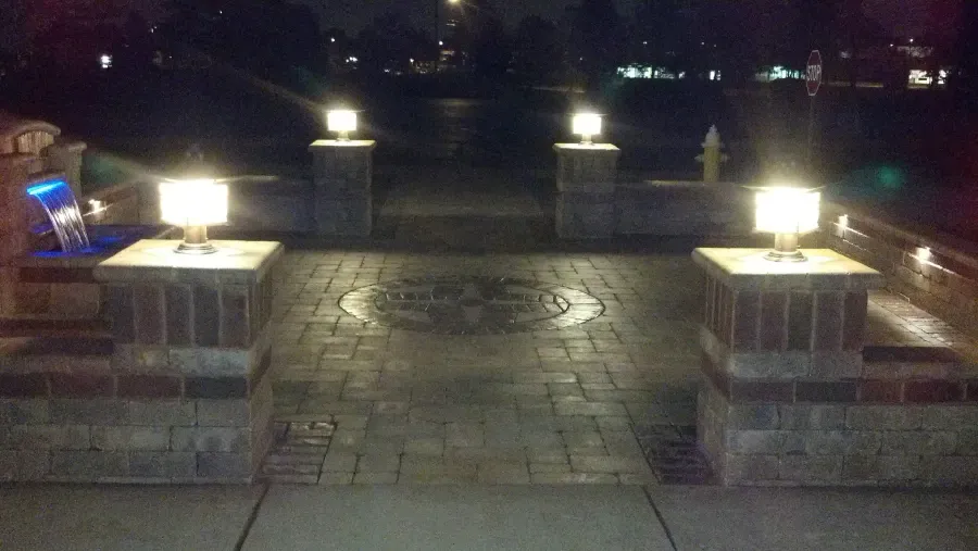 A brick walkway with lights on it at night