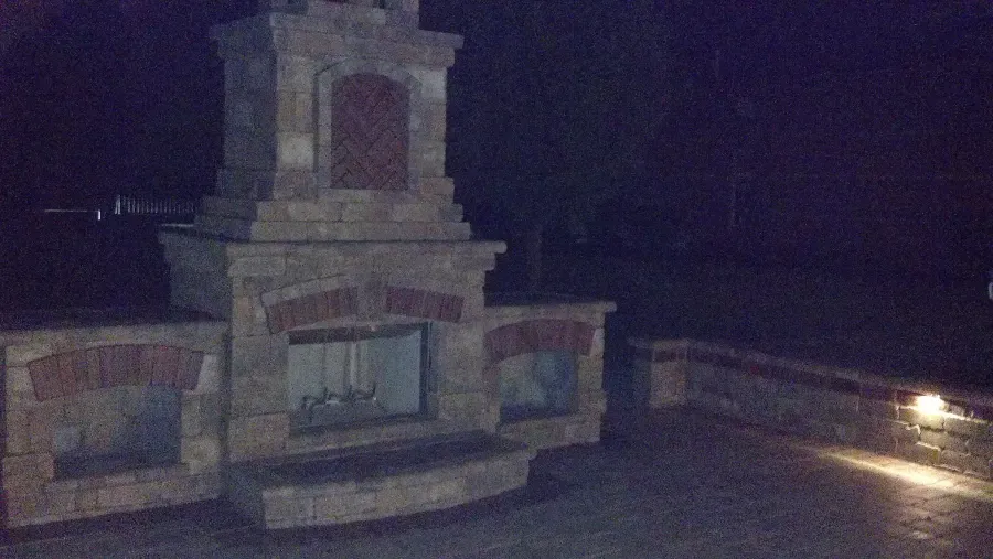 A large stone fireplace is lit up at night