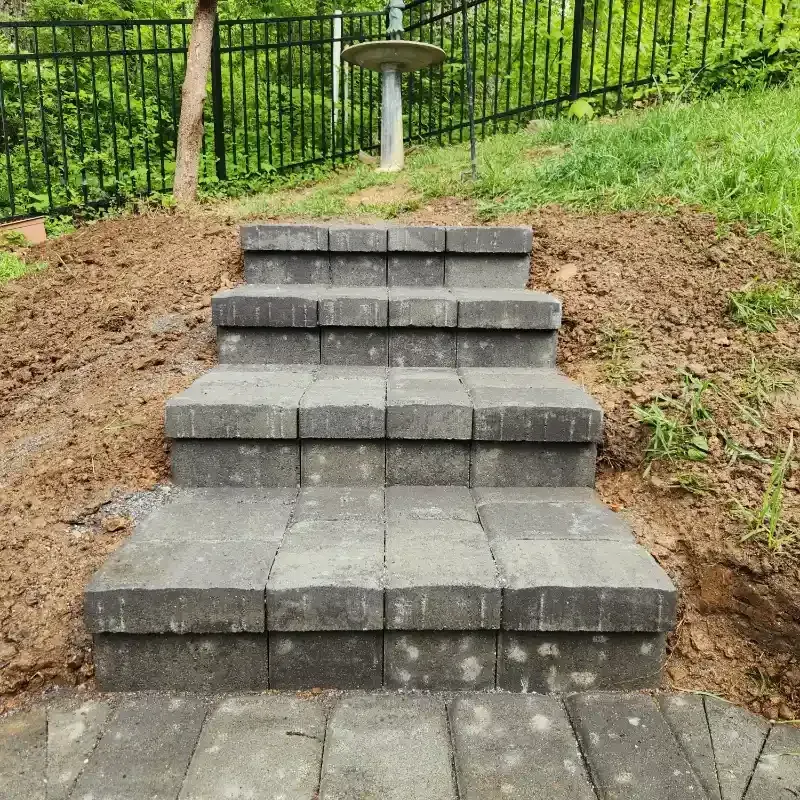 A set of stairs going up a hill with a fence in the background