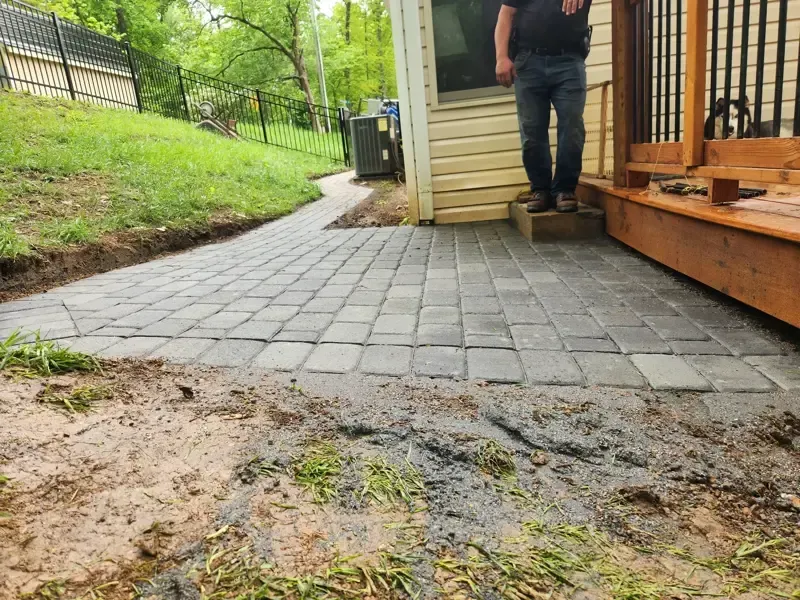 A man is standing on a brick walkway next to a house.