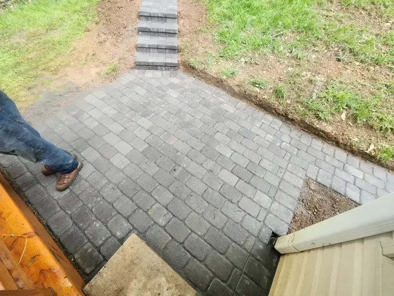 A person is walking down a brick walkway next to a house.