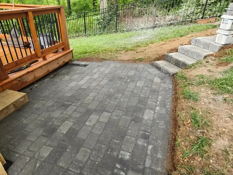 A patio with stairs and a wooden deck in the background.