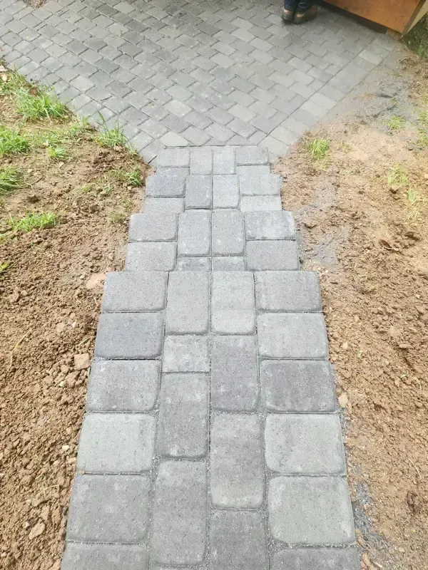 A person is standing on a sidewalk made of bricks
