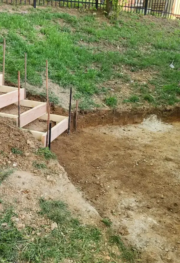 A wooden staircase is being built in the dirt in a yard.