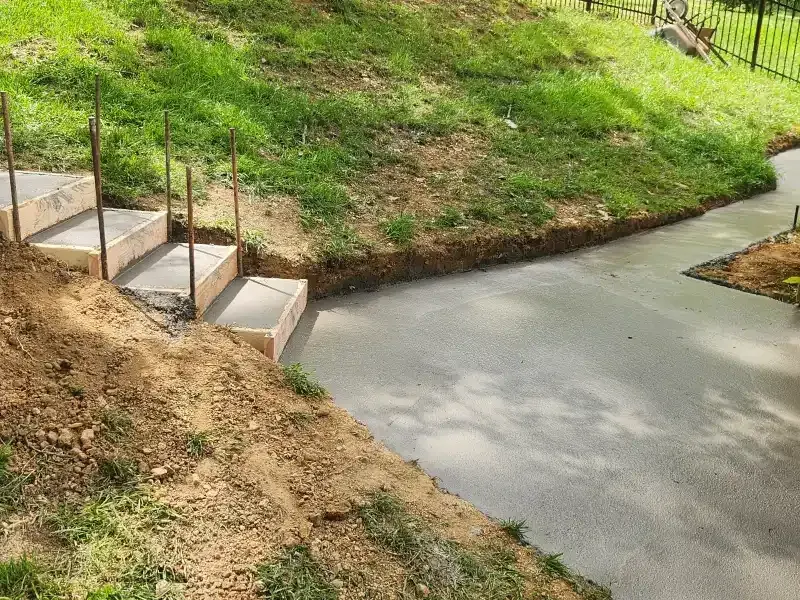 A concrete walkway with stairs going up a hill.
