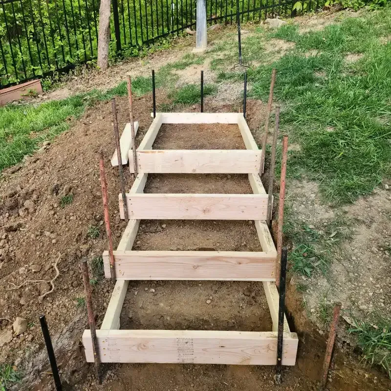 A row of wooden steps are being built in the dirt.