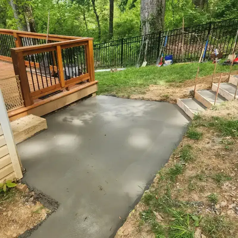 A concrete walkway is being built next to a wooden deck.