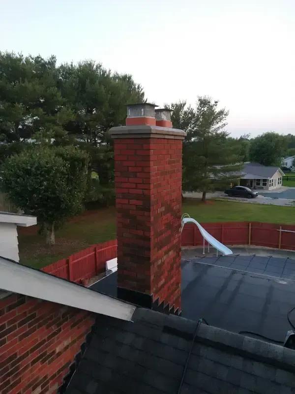 A brick chimney is on the roof of a house