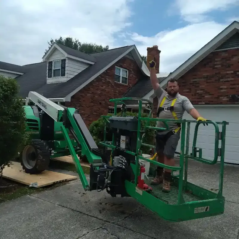 A man is standing in a green lift holding a piece of wood