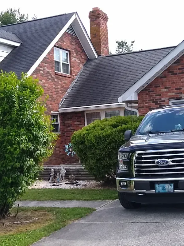 A black ford truck is parked in front of a brick house