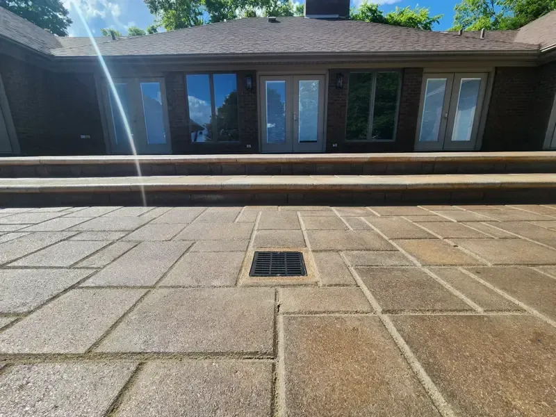 A brick patio with steps leading up to a house.