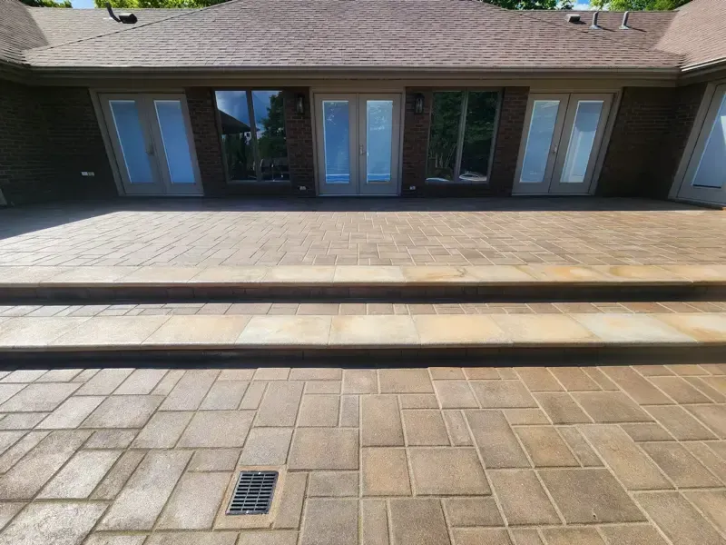 A brick patio with stairs leading up to a house