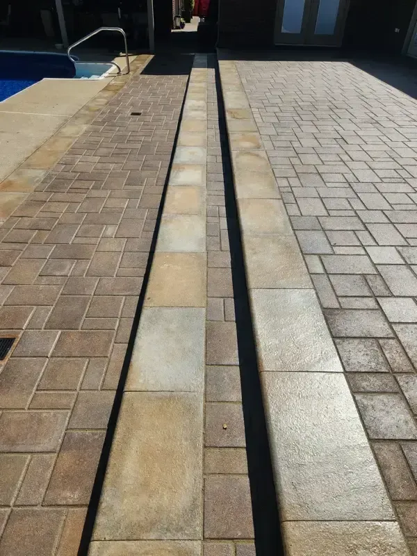 A brick walkway next to a swimming pool