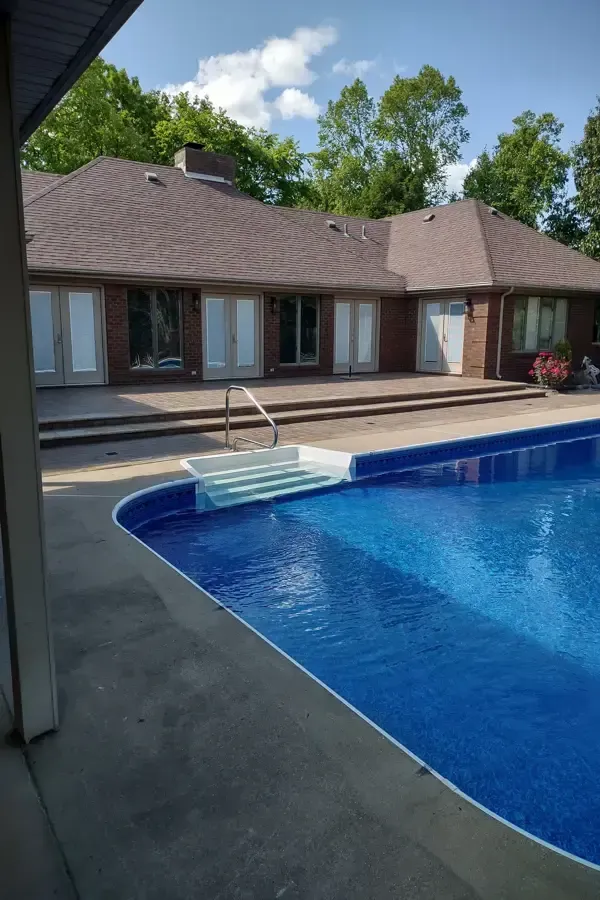 A large swimming pool is in the backyard of a house.