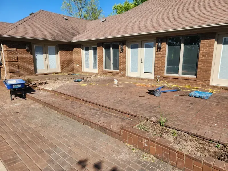 A blue wheelbarrow is parked in front of a brick house.