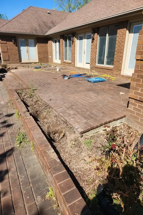 A brick walkway is being built in front of a brick house.