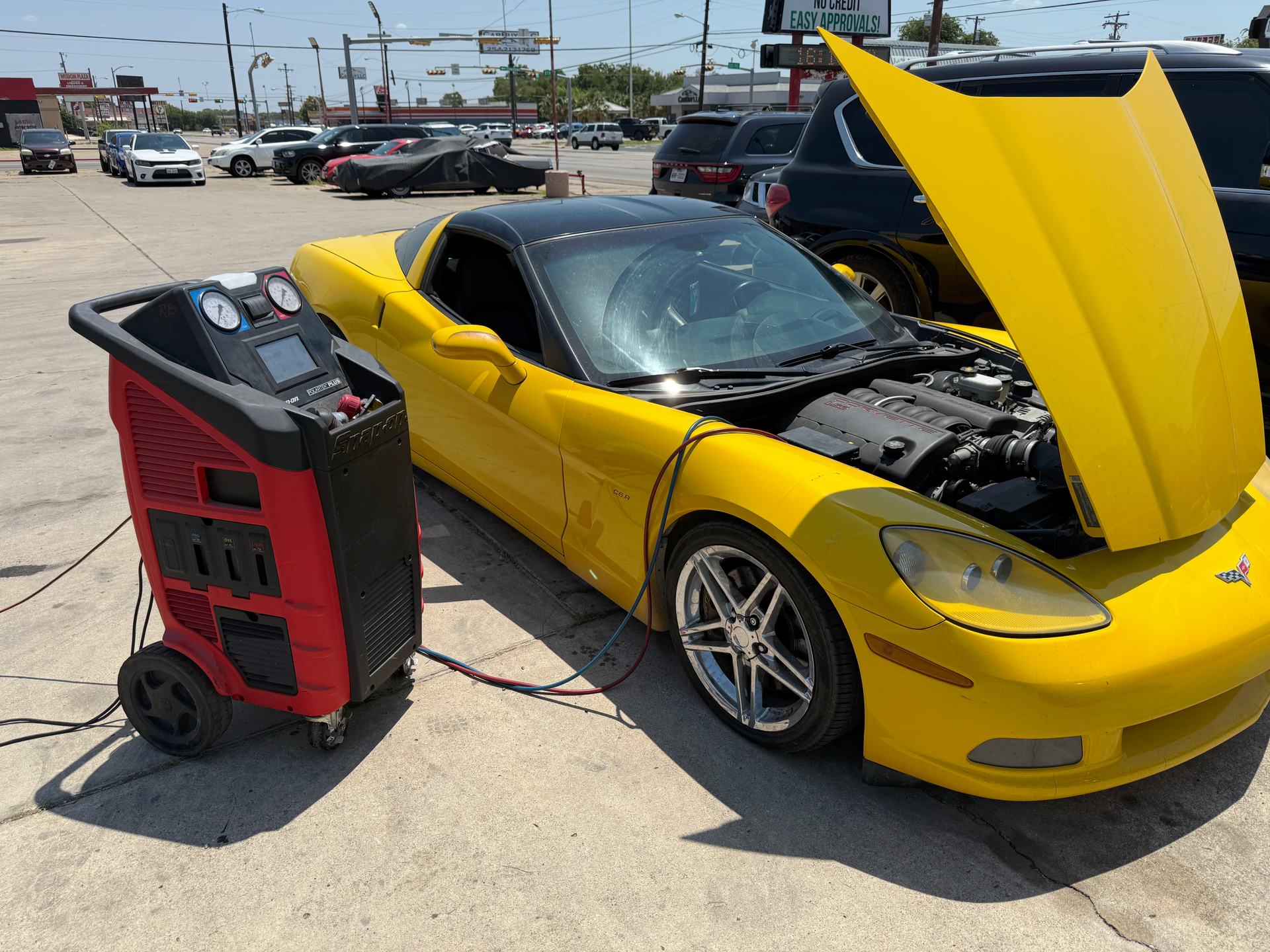 Yellow Corvette being serviced outdoors, connected to an A/C machine. | Auto Masters Repair Shop
