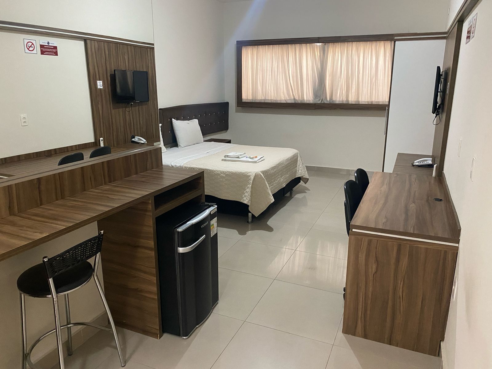 Um quarto de hotel com duas camas, uma escrivaninha e uma geladeira.