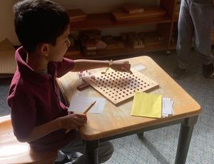 Child using Montessori bead board to learn multiplication and explore number patterns hands-on.