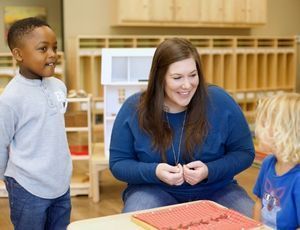 Montessori teacher interacting warmly with children, modeling language and behavior absorbed in earl