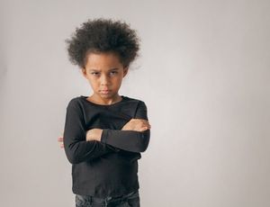 Child with crossed arms and an upset expression, showing big emotions during a challenging moment.
