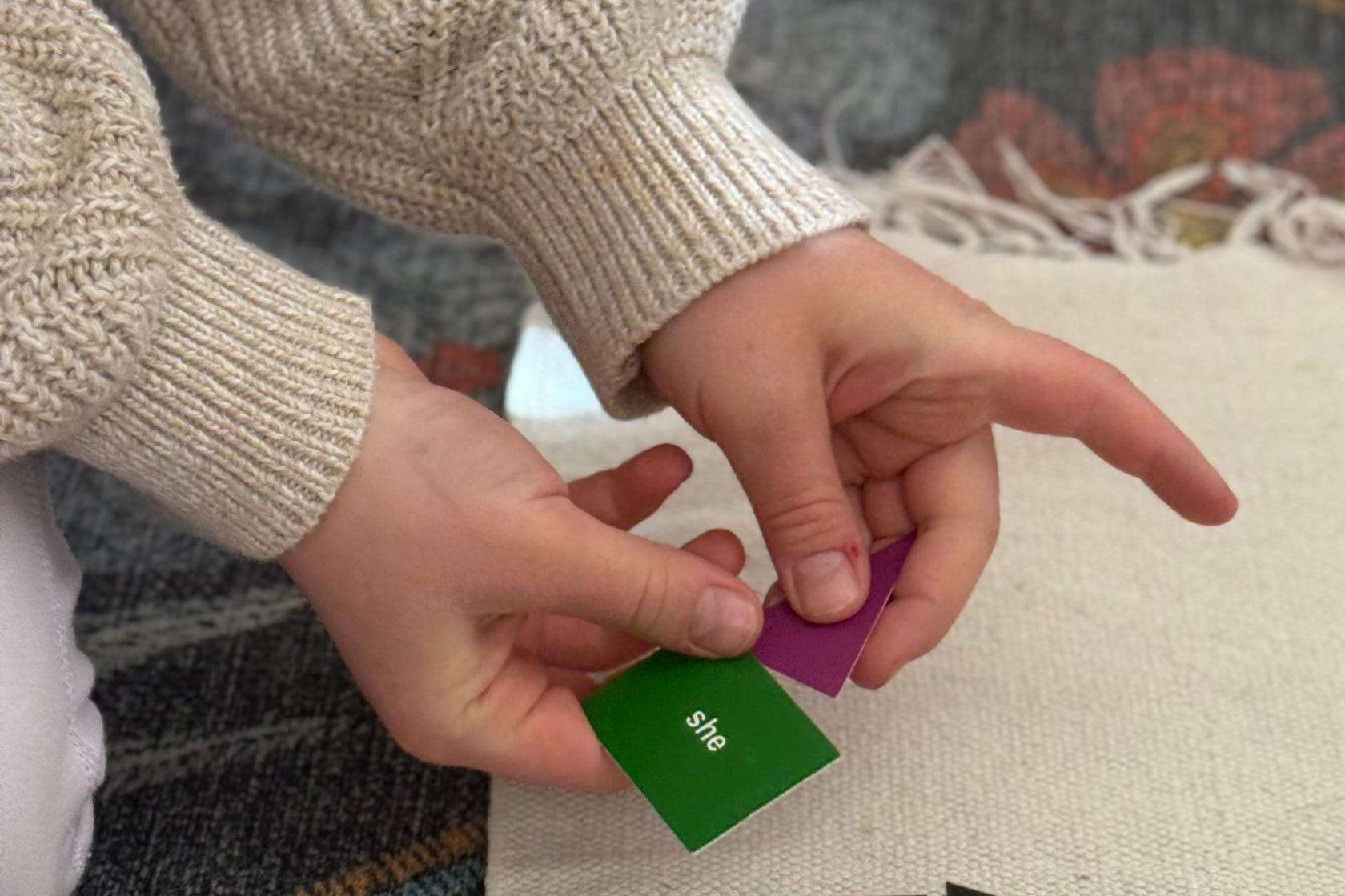 Child using color-coded word cards to explore pronouns in a Montessori language activity.
