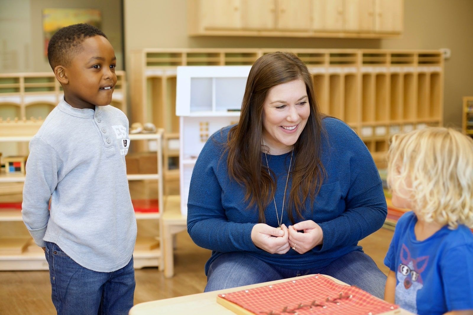 Montessori teacher interacting warmly with children, modeling language and behavior absorbed in early childhood.