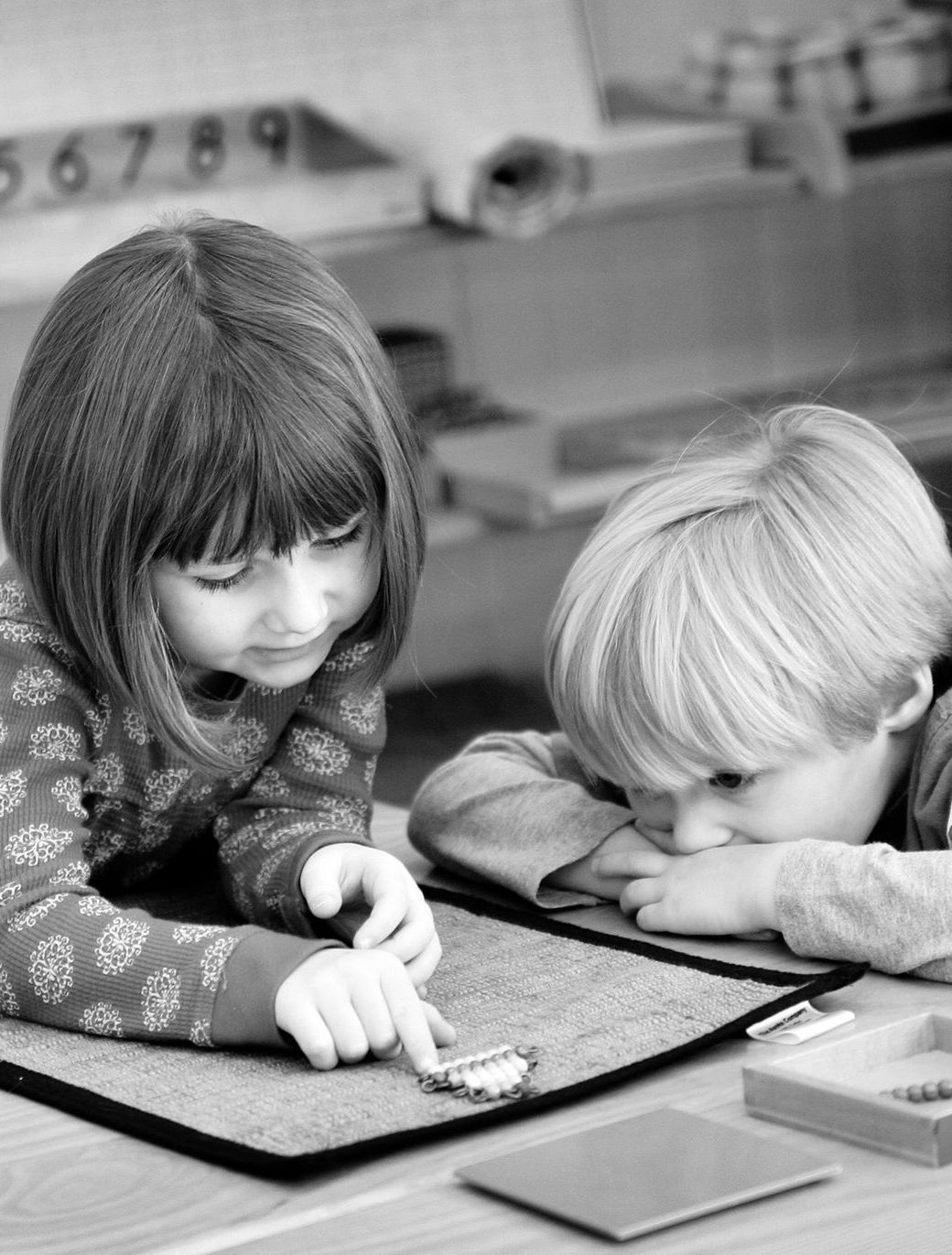 Two children engage with Montessori math learning materials.