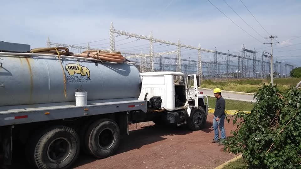 Camión cisterna cerca de una central eléctrica; un trabajador con casco de seguridad se encuentra cerca.
