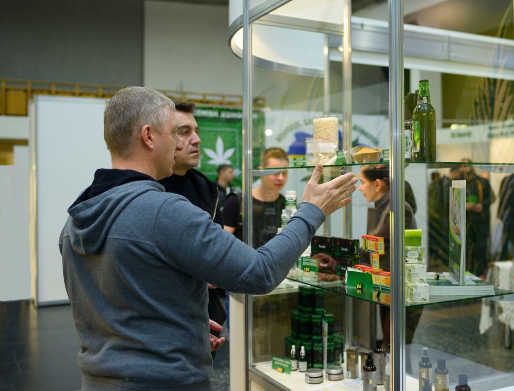 A man is standing in front of a glass display case looking at something.