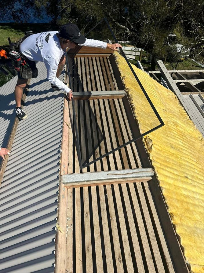 A Man is Working on the Roof of a Building — Northern Rivers Metal Roofing PTY LTD In Ewingsdale, NSW