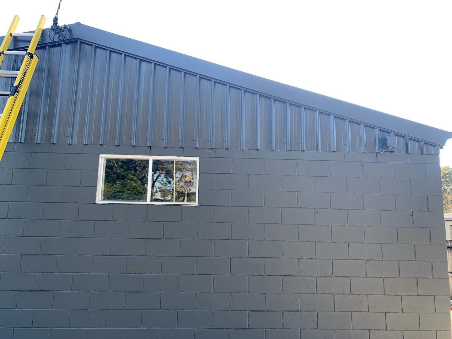 A Ladder is Hanging From the Side of a Building — Northern Rivers Metal Roofing PTY LTD In Brunswick Heads, NSW