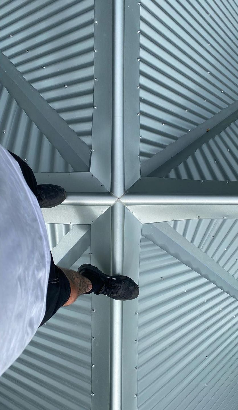 Two Construction Workers Are Working on the Roof of a Building — Northern Rivers Metal Roofing PTY LTD In Ewingsdale, NSW