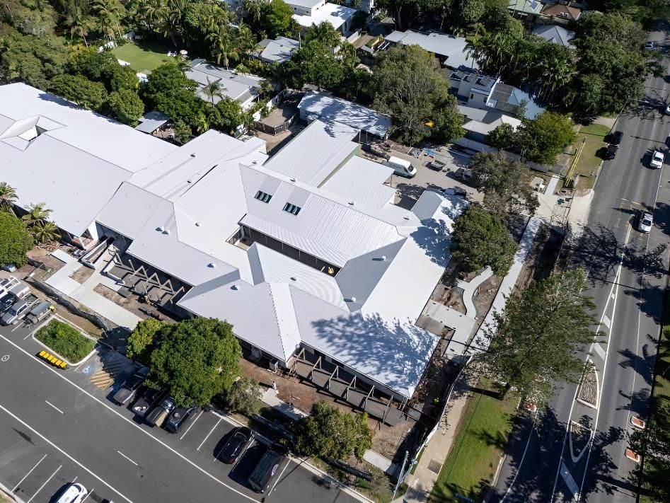 Light-roofed Building Surrounded by Trees and a Road With Cars — Northern Rivers Metal Roofing PTY LTD In Tweed Heads, NSW