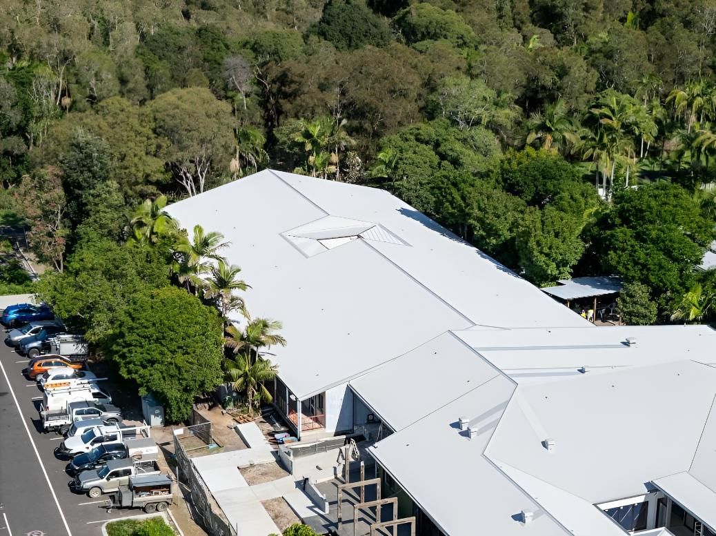 Building With a Large White Roof, Surrounded by Trees — Northern Rivers Metal Roofing PTY LTD In Coffs Harbour, NSW