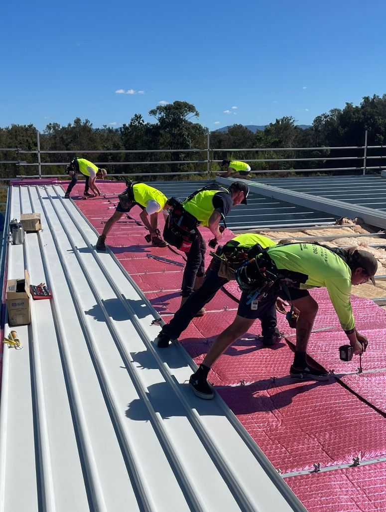 A Group of Construction Workers Are Working on a Roof  — Northern Rivers Metal Roofing PTY LTD In Ewingsdale, NSW