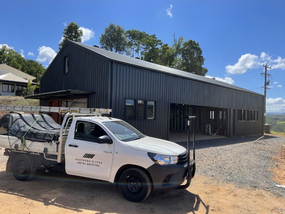 A White Truck is Parked in Front of a Large Building  — Northern Rivers Metal Roofing PTY LTD In Ewingsdale, NSW