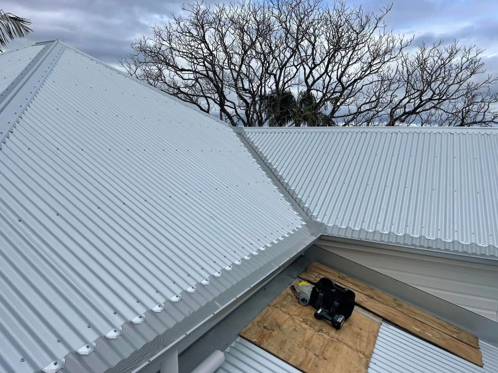 A White Corrugated Metal Roof is Being Installed on a House — Northern Rivers Metal Roofing PTY LTD In Ewingsdale, NSW