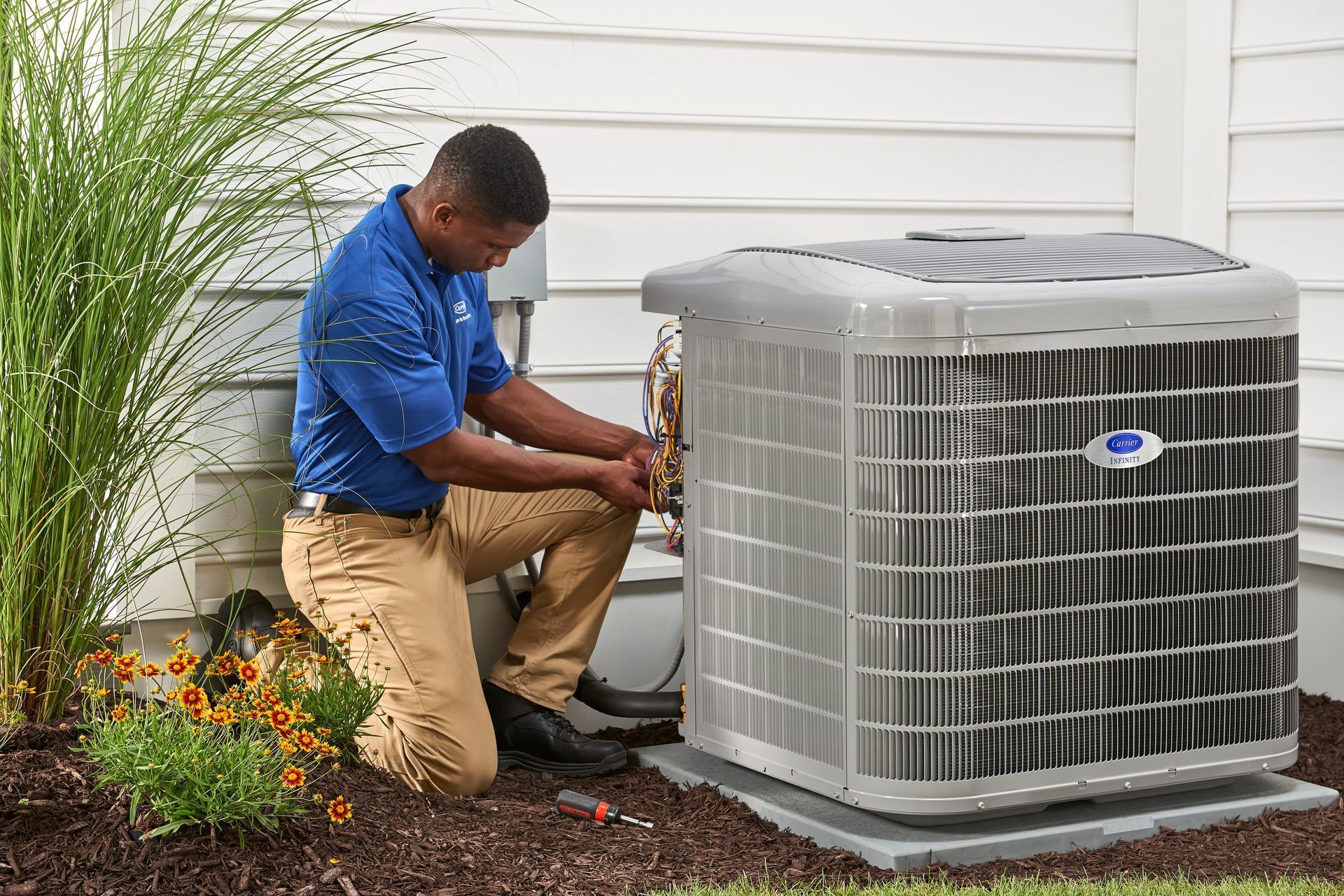 A man is working on an air conditioner outside of a house.