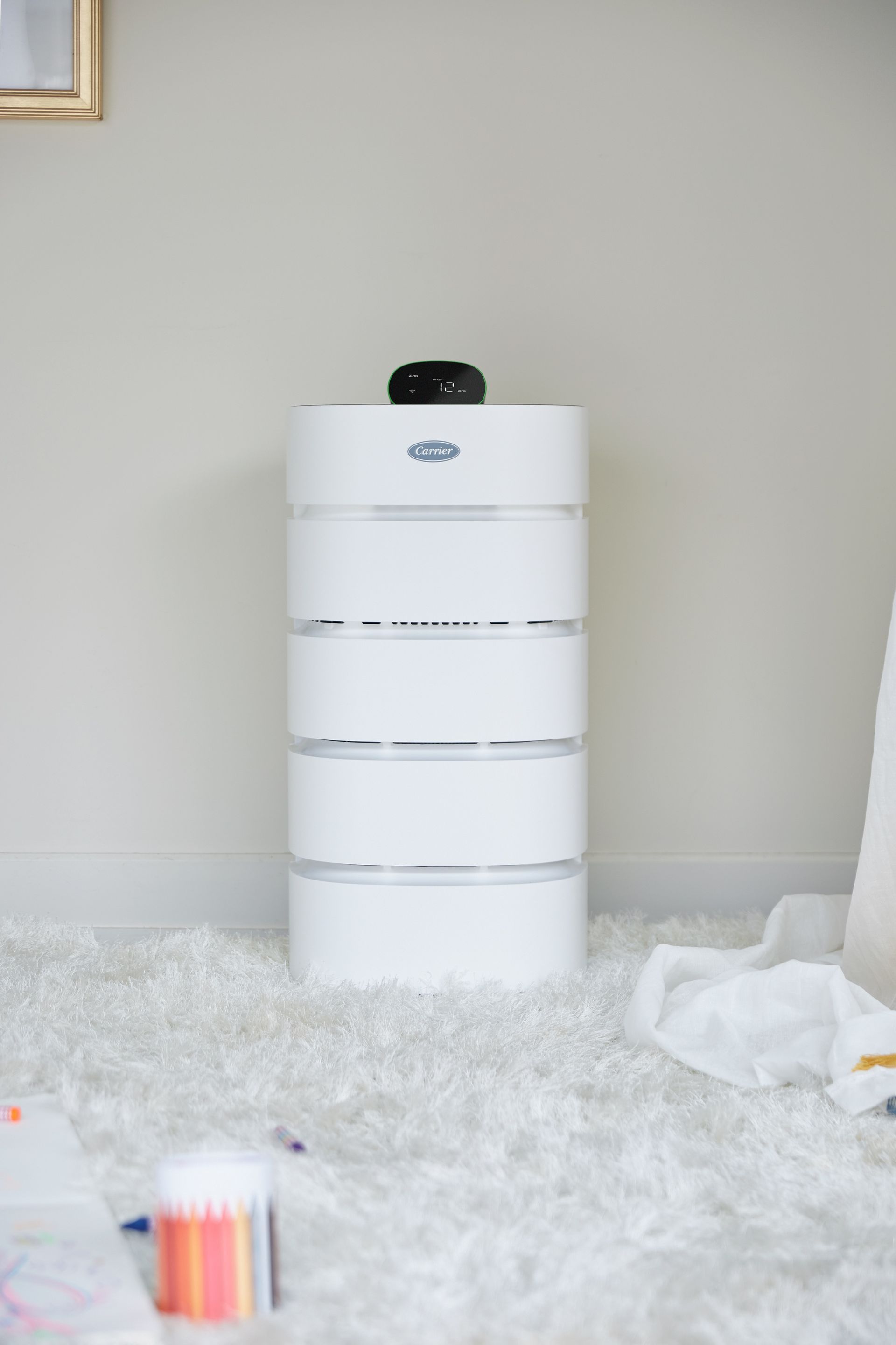 A white air purifier is sitting on a white rug in a room.