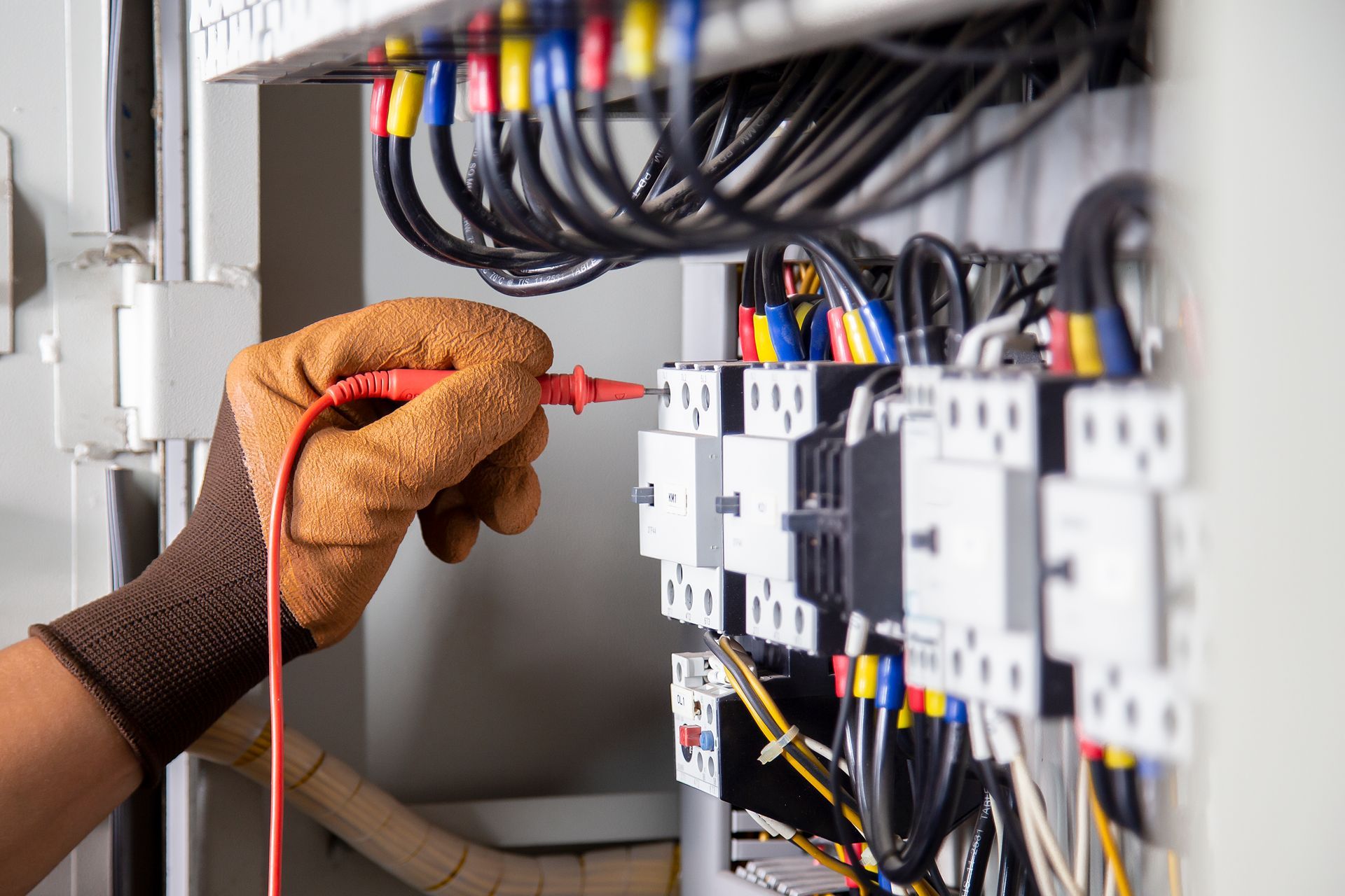 An electrician is working on an electrical box with a multimeter.