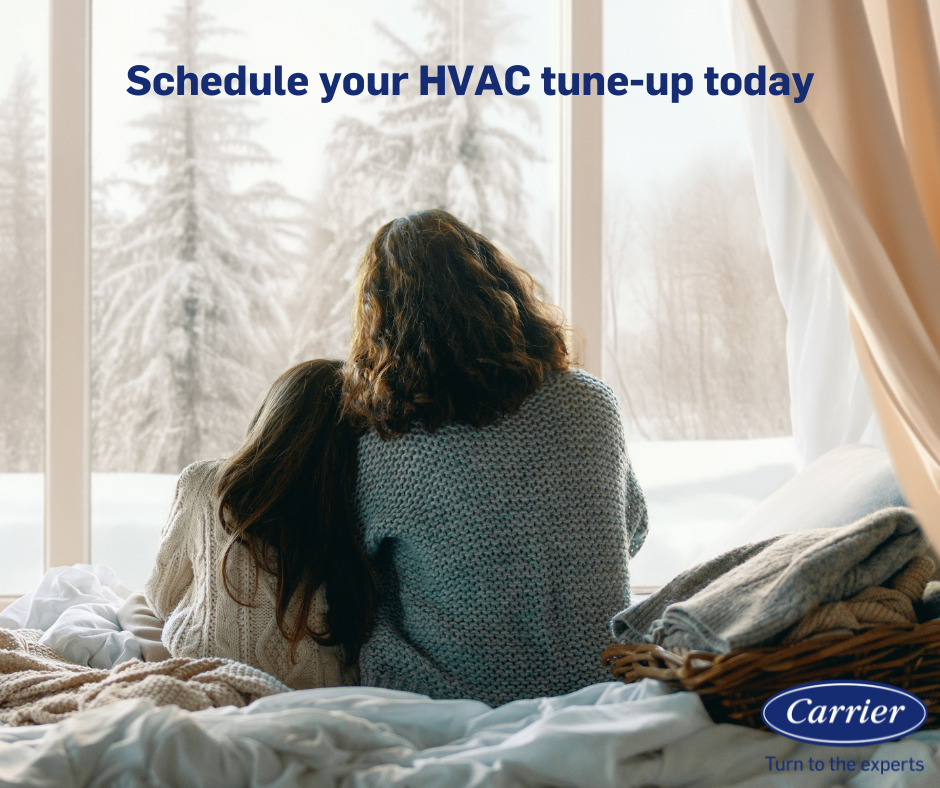 Mother and child look out a window at a snowy scene. Text: Schedule your HVAC tune-up today. Carrier logo.