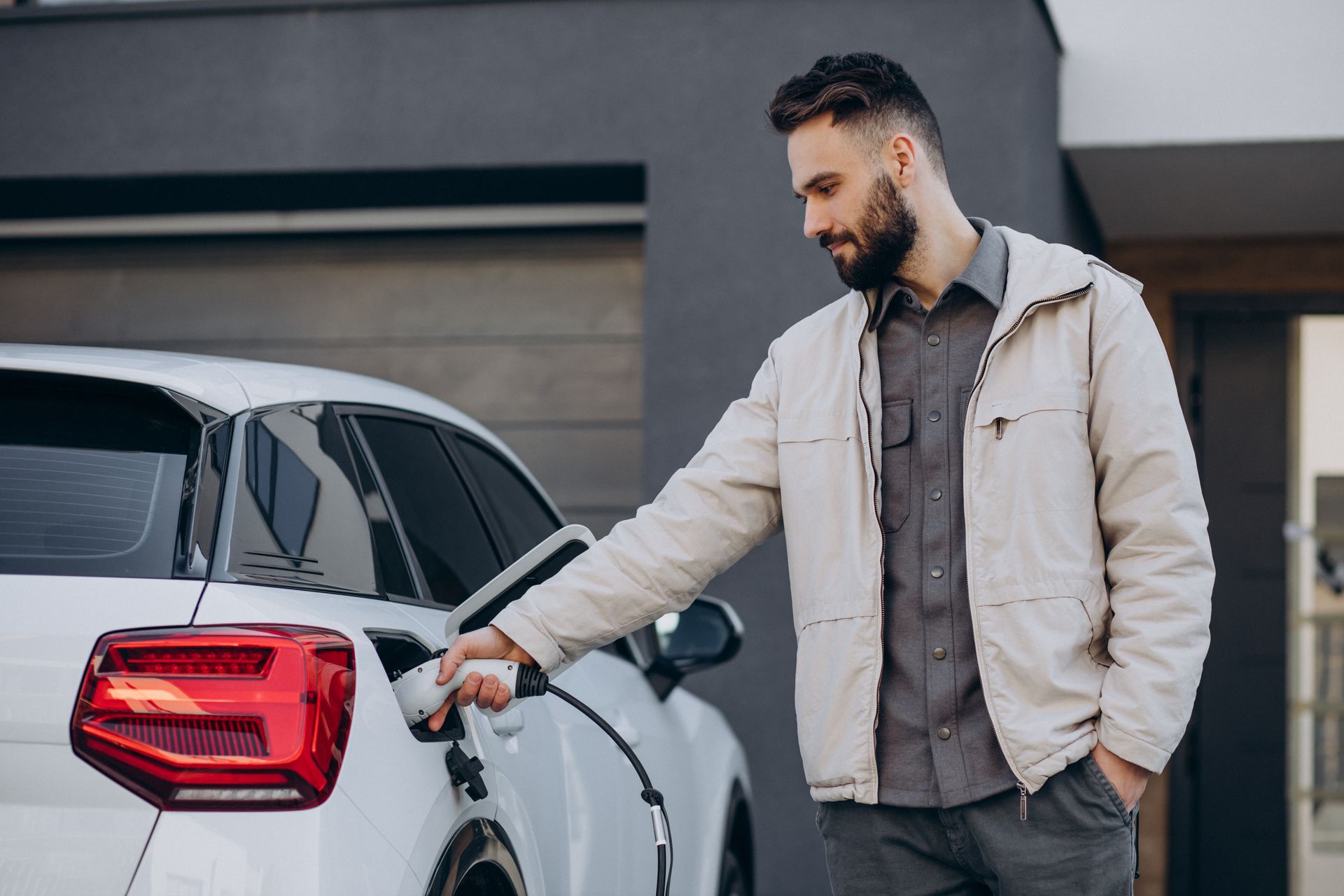 A man is charging his electric car at a charging station.