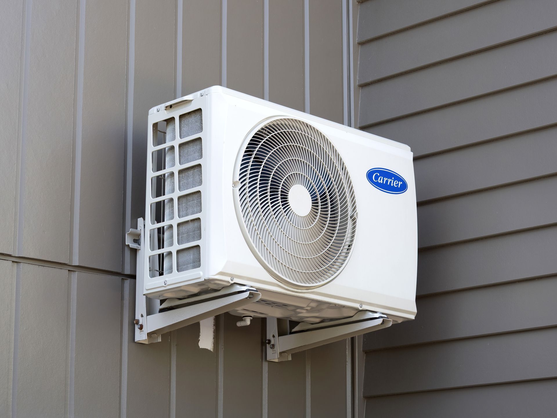 White Carrier air conditioner unit mounted on a gray building exterior.