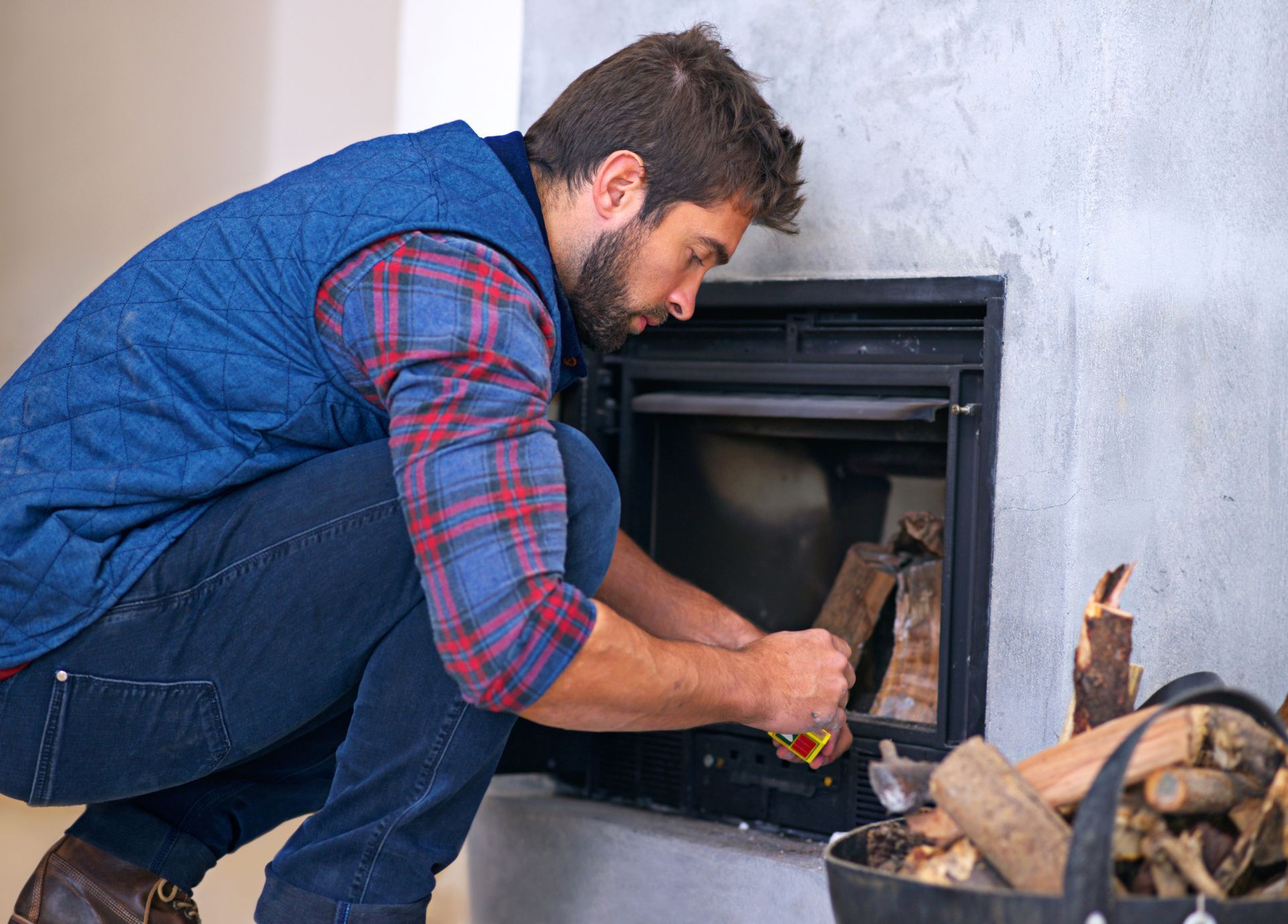 A man is kneeling down in front of a fireplace in a living room.