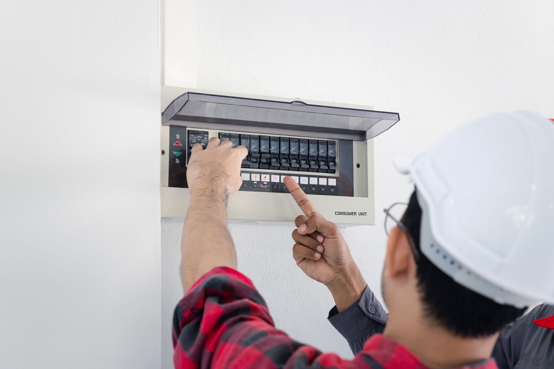 A man in a hard hat is working on an electrical box.