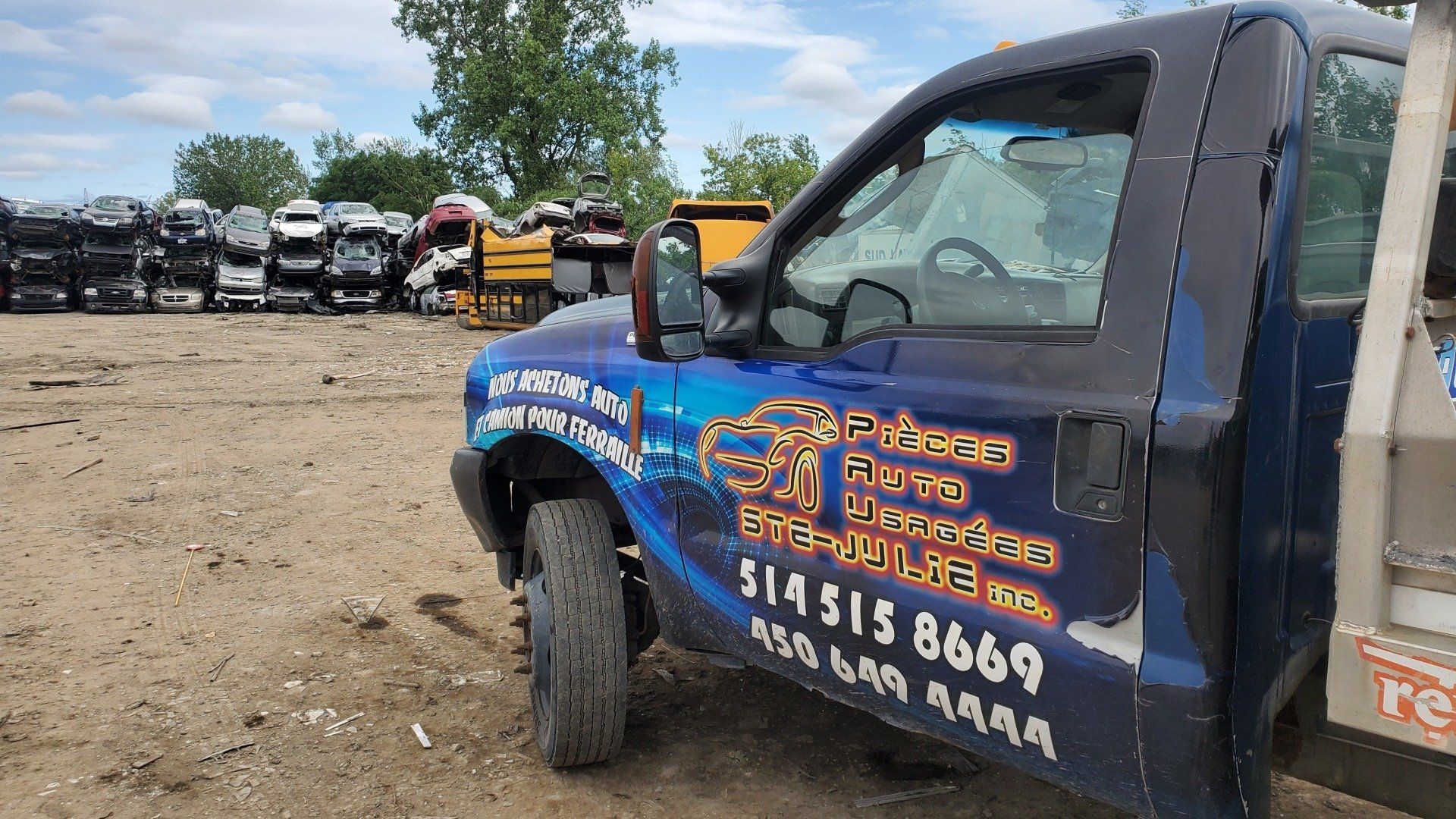 Une dépanneuse bleue est garée dans une casse.