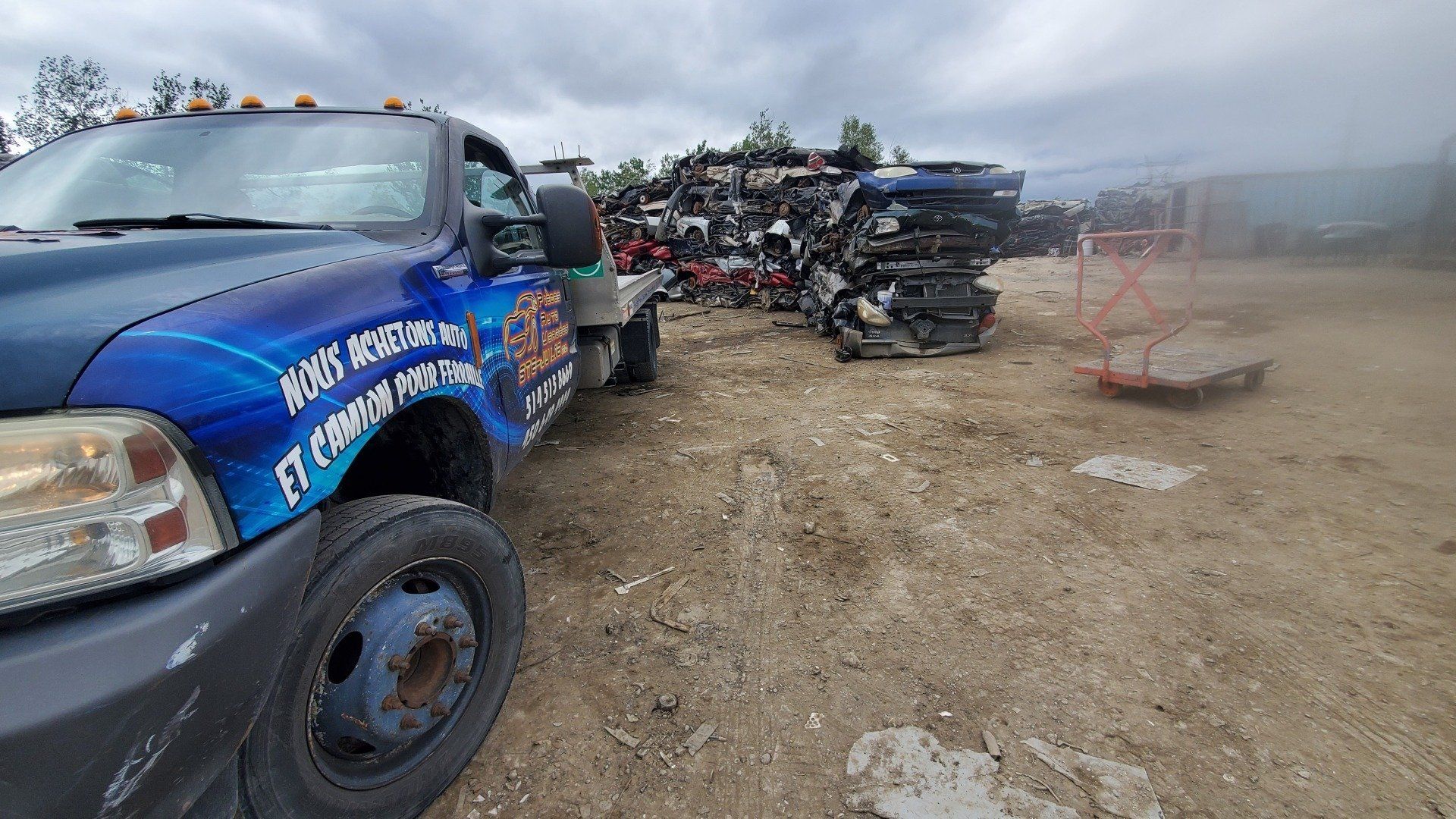Une dépanneuse bleue est garée dans un tas de ferraille.
