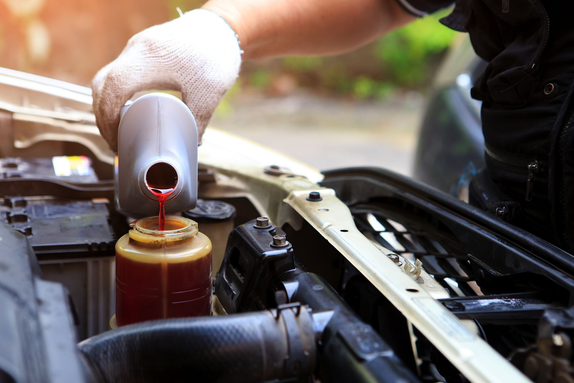 A person is pouring fluid into a car reservoir.