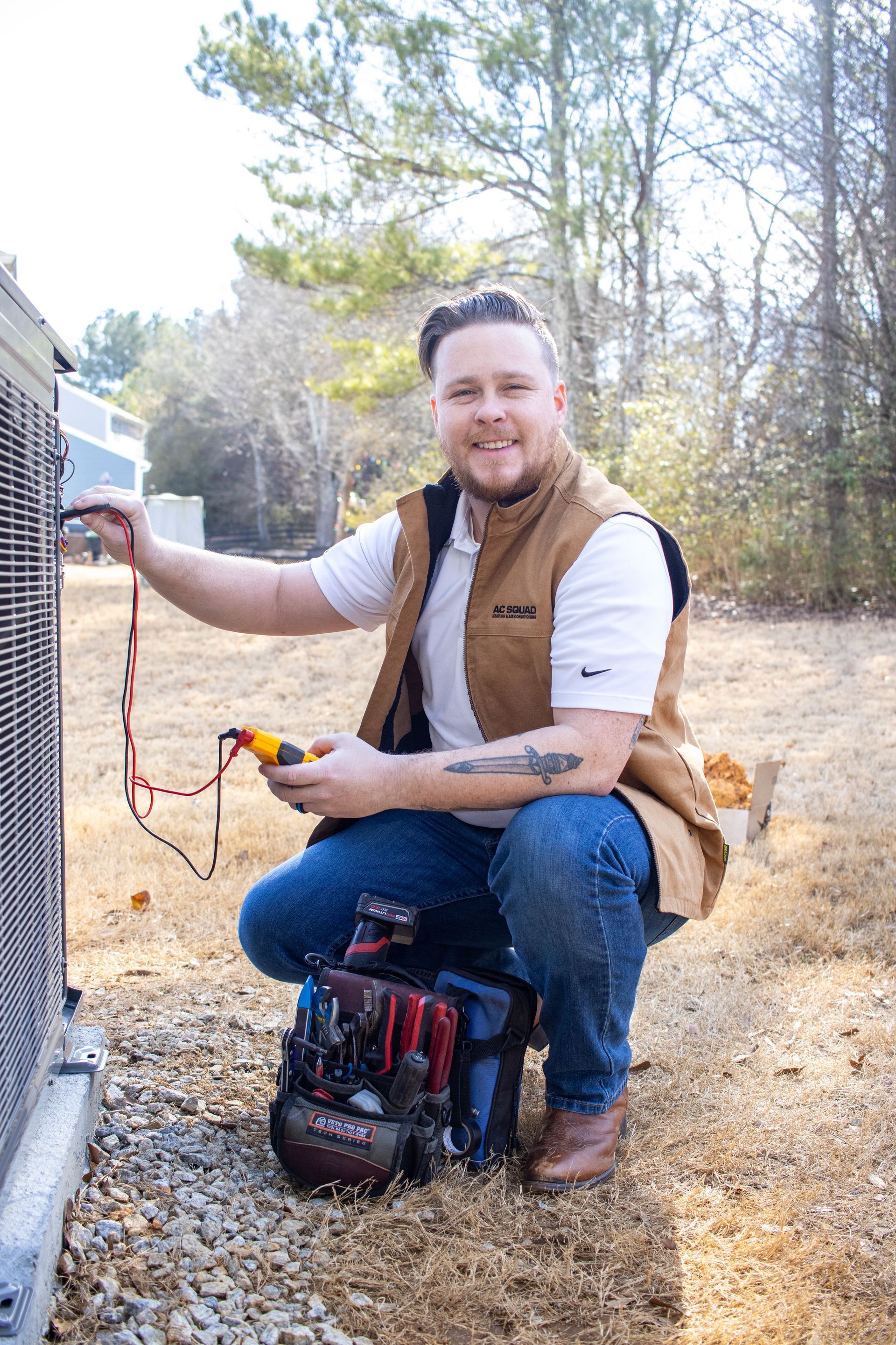 Two air conditioners are sitting on gravel outside of a house.